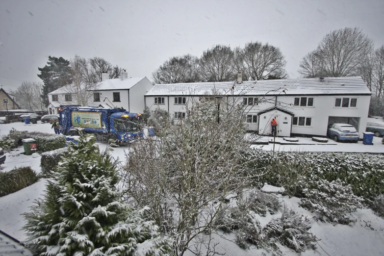 a group of houses and trucks parked on a snow covered road