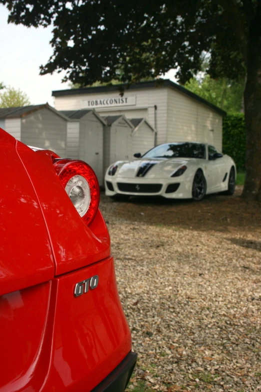 an old race car and a sports car are parked outside a barn