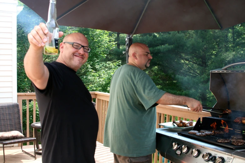 two men standing around on a deck cooking food