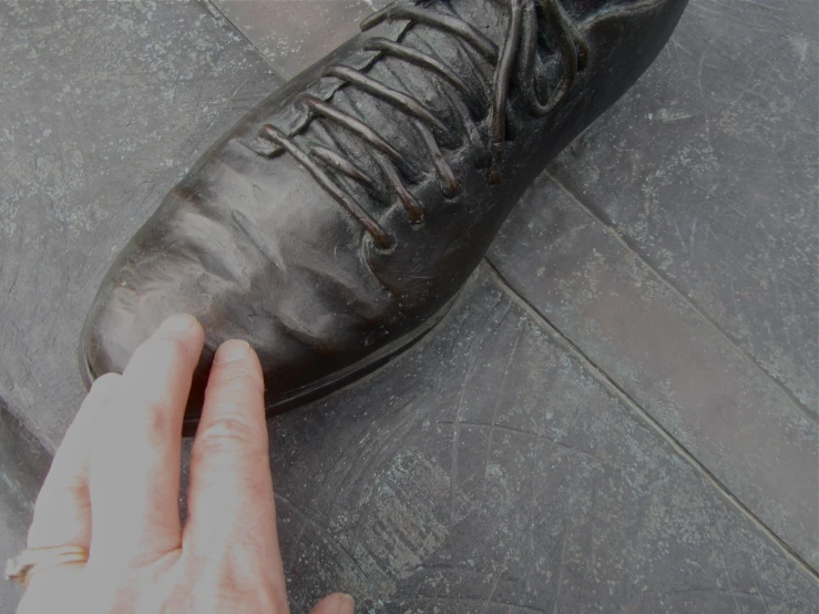 a man who is touching a shoe that has the lace off