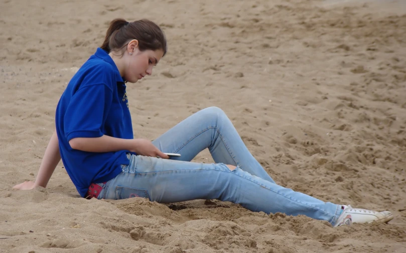 a  sitting on the beach, with her phone