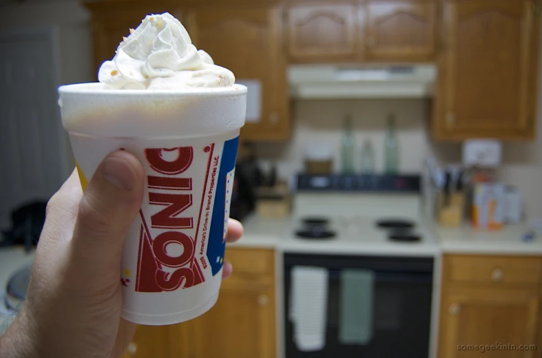 someone holding up a cup in a kitchen