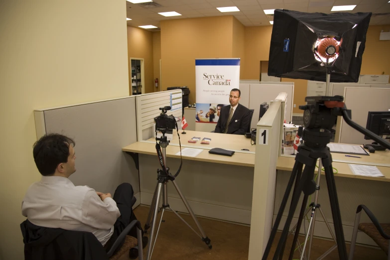 people with cameras, lights and lighting equipment sitting in an office cubicle