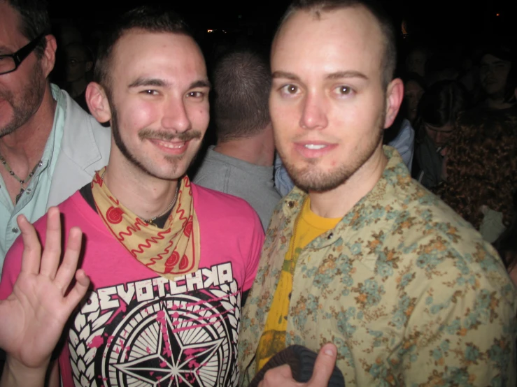 two men standing together at a party with their hands up