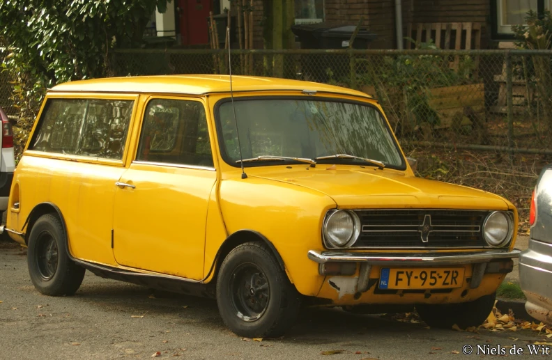 a bright yellow car in front of a fence