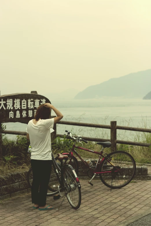 a man looking out over the water next to his bicycle