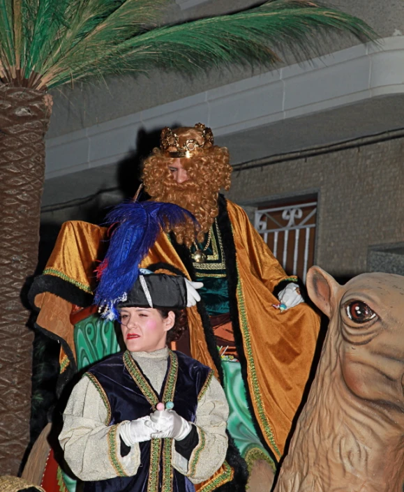 a boy stands next to a statue of an ancient man in costume