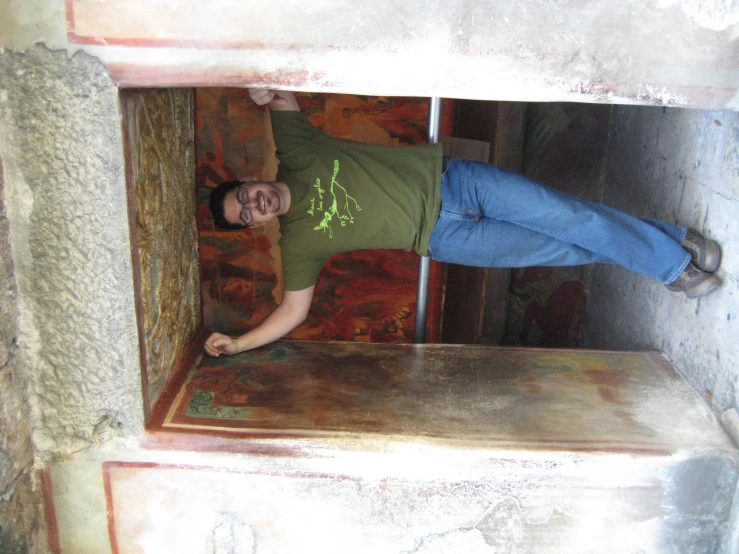 man in tan shirt and jeans standing in doorway