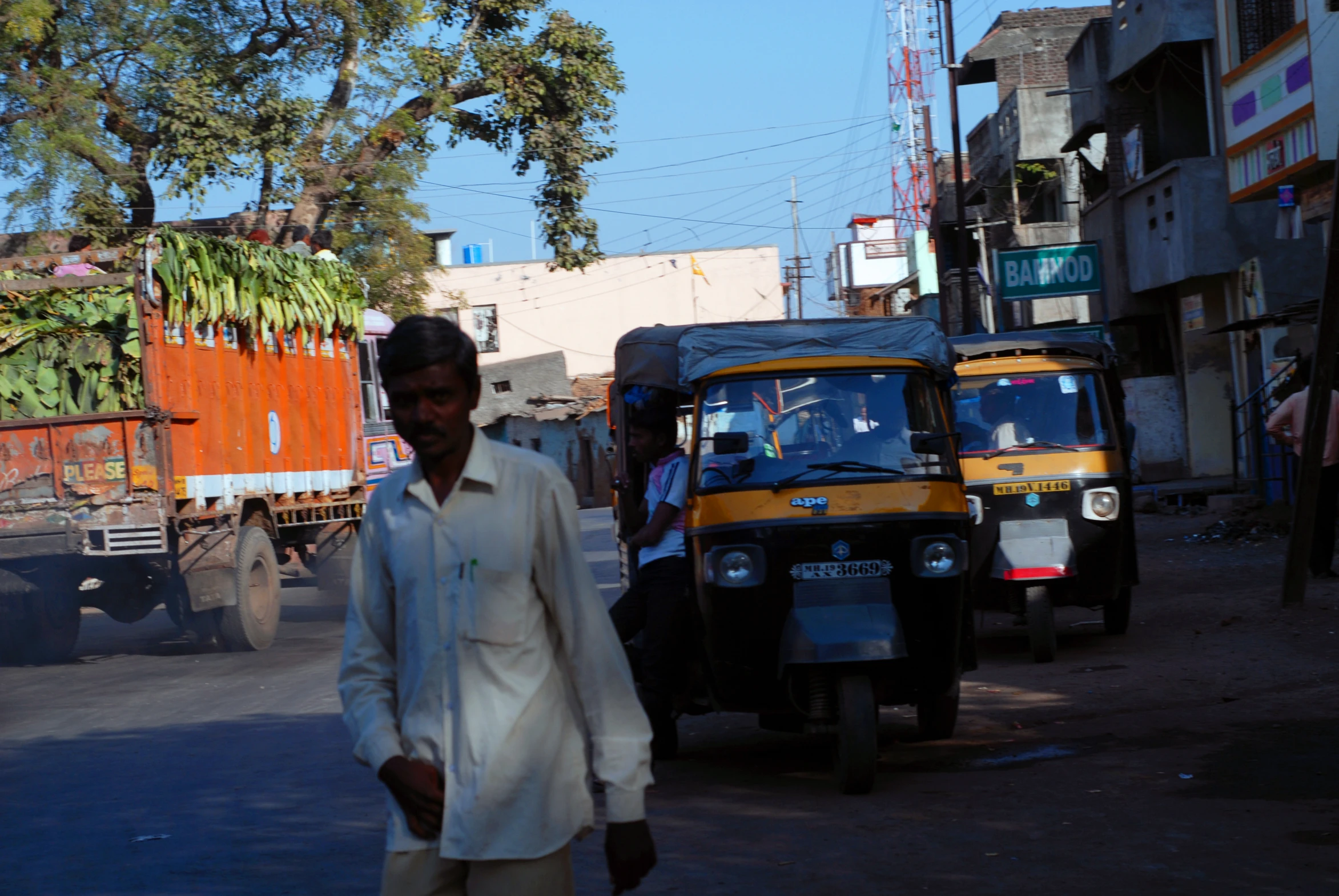 a man walking down the street with two parked trucks