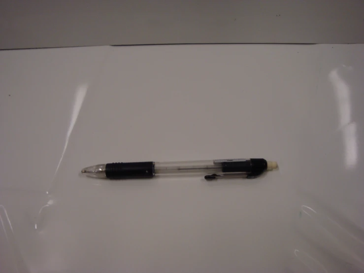 two pens resting on top of each other on a white table