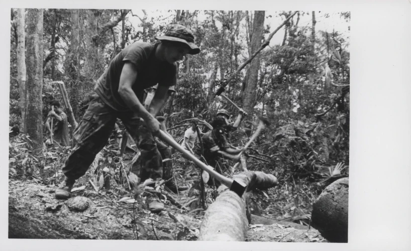 man with stick trying to throw fire up logs