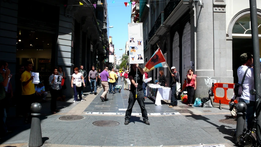 people walking down an urban street with flags on the sidewalk