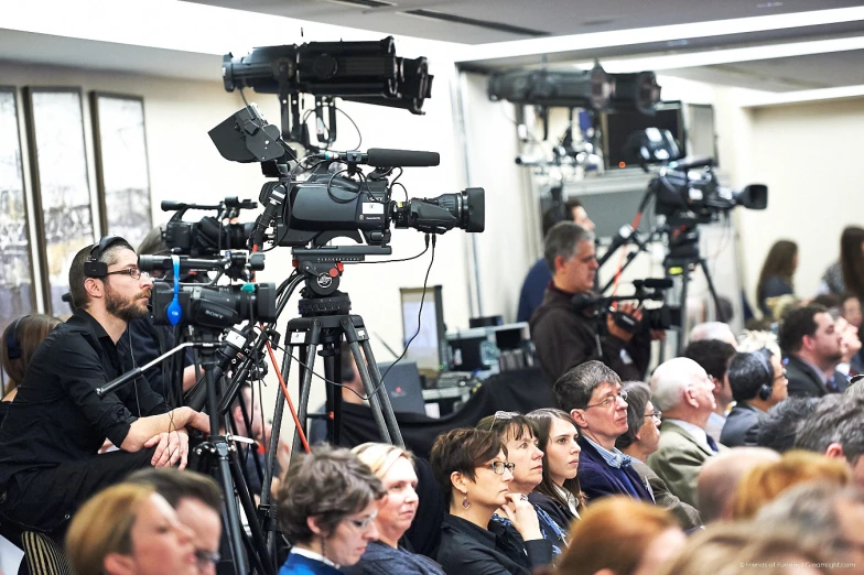 several people sitting in a room with cameras in their laps