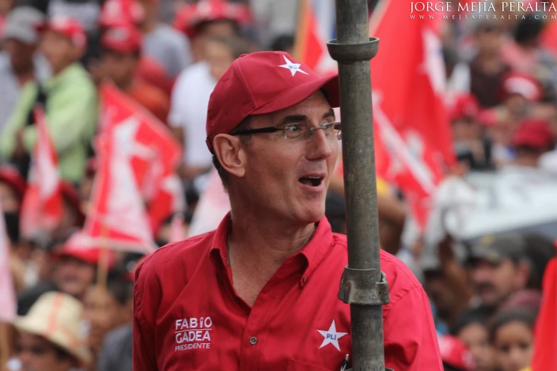 man standing next to pole holding flags on open air area