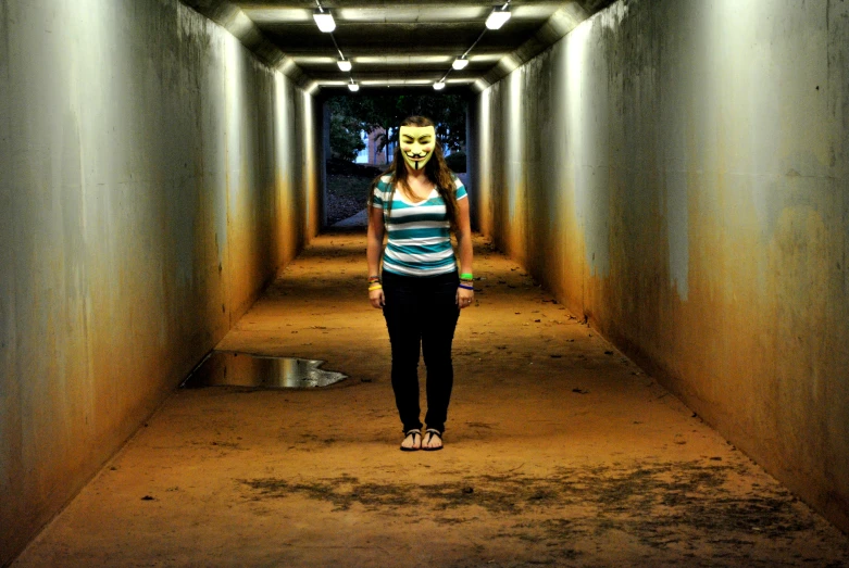 a woman walking through a tunnel with a creepy mask on