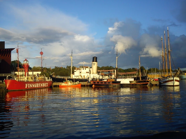 boats in a harbor at sunset with clouds in the background