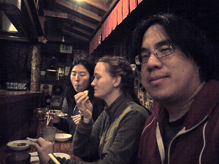three people sitting around a bar eating together
