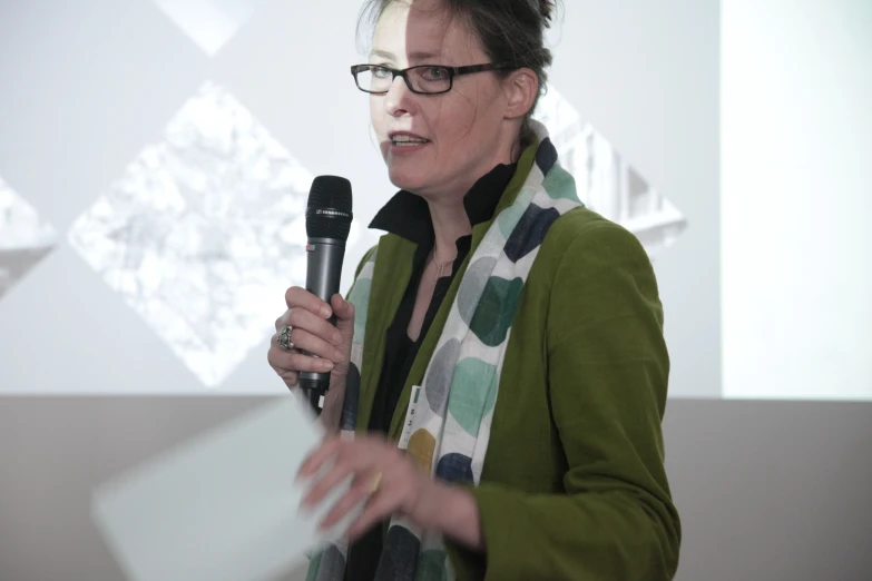 an older woman talking on a microphone with a patterned scarf