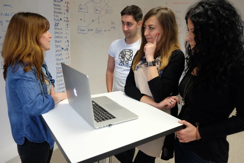 four young women are standing by a whiteboard with white writing on it