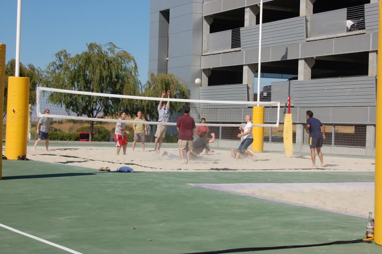 people playing volleyball on the court next to a stadium