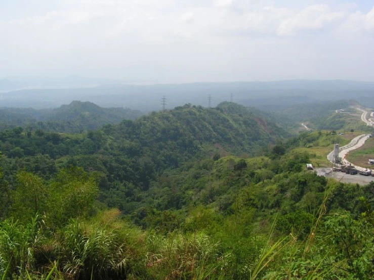 a scenic road with lots of green hills in the background