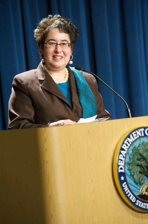 woman standing in front of a podium wearing glasses