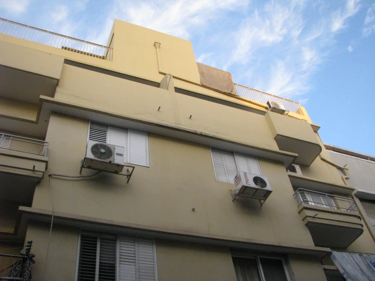 the side of an apartment building with windows and balcony fan and shutters