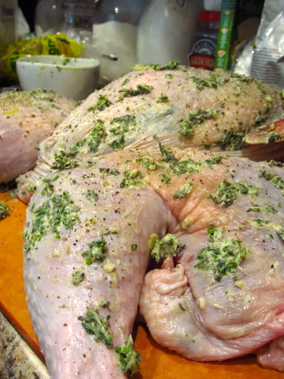 large piece of meat covered in herbs on wooden  board