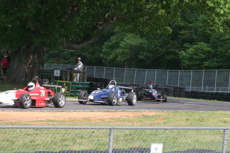 three cars racing down a track in a race