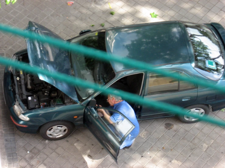 a man sits in the driver's seat of a car parked next to another car