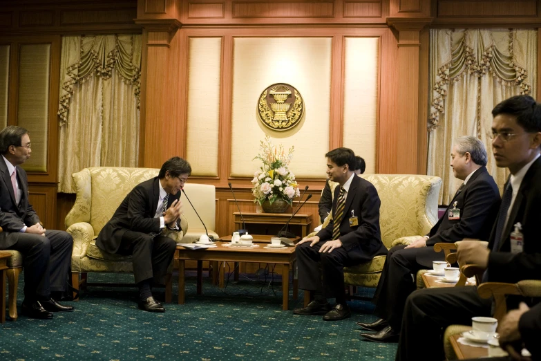 five men sitting in the middle of a room together