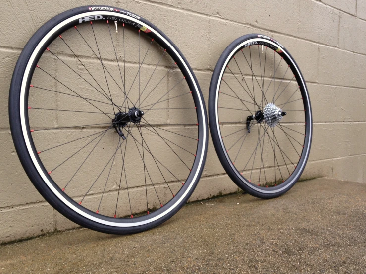 two rear and back bicycle wheels, one of which is on the wall