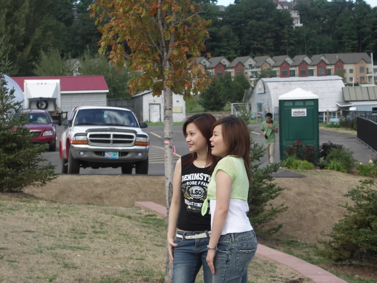 two asian women looking at each other with a street view