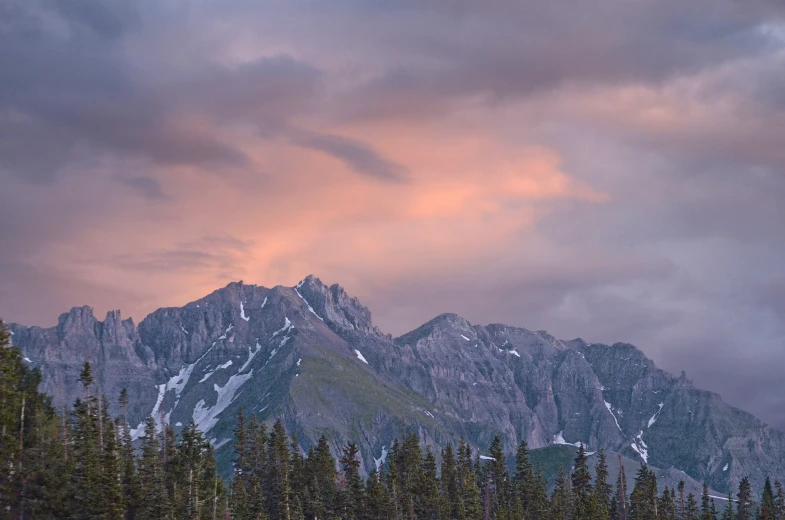 a mountain covered in a layer of snow under a cloudy sky