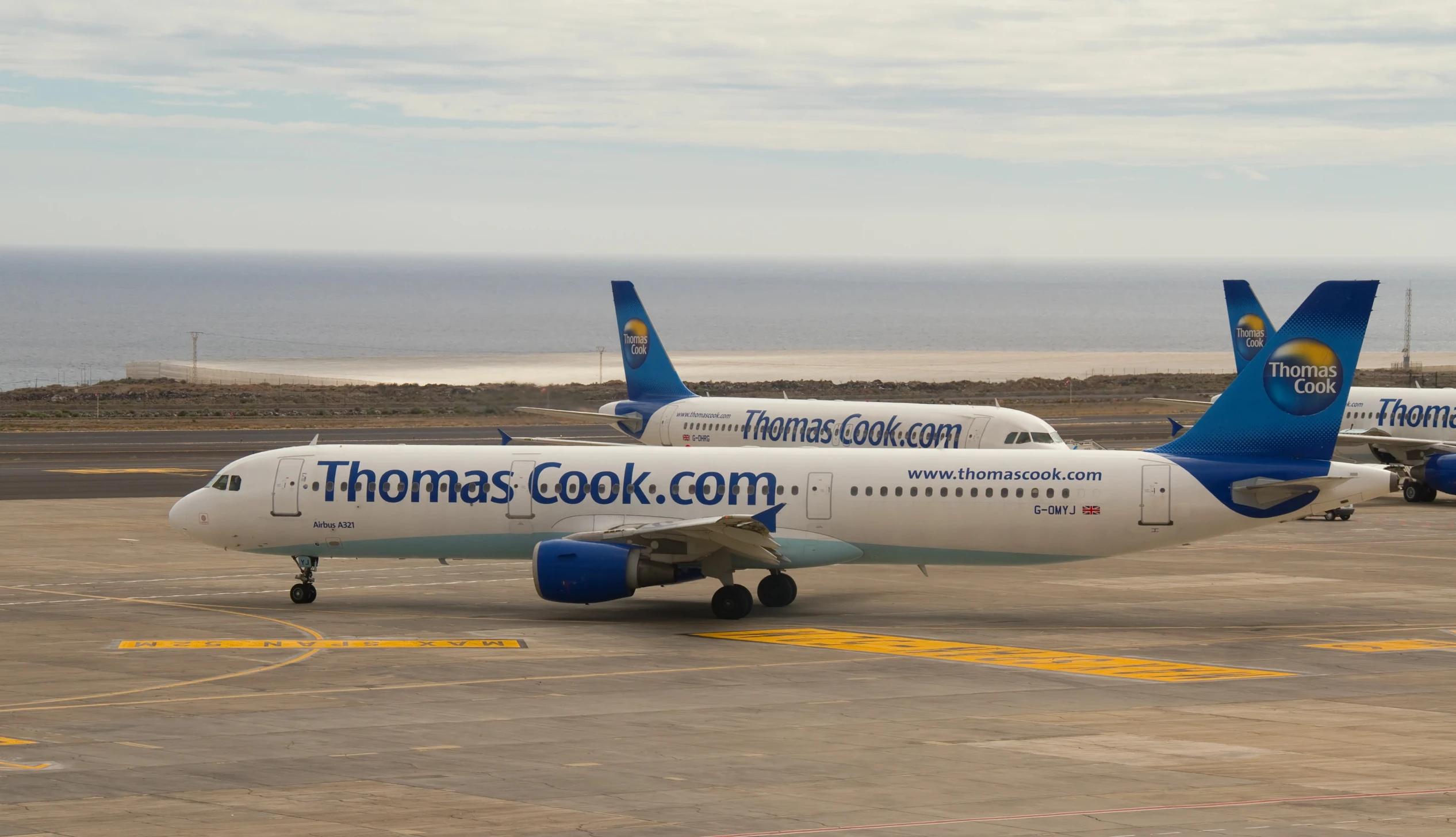 two thomas cook airplanes on a runway near the ocean