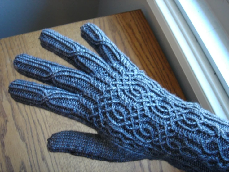 a blue knitted hand on top of a wooden surface