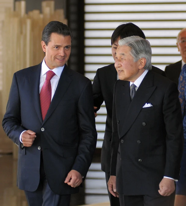 two men dressed in suits and ties with other men in suits