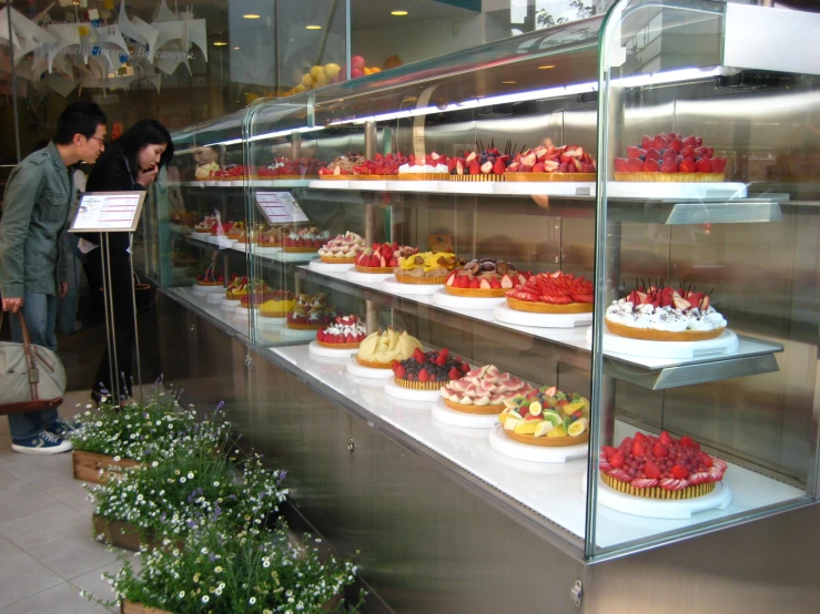 people in a bakery looking at different types of cupcakes