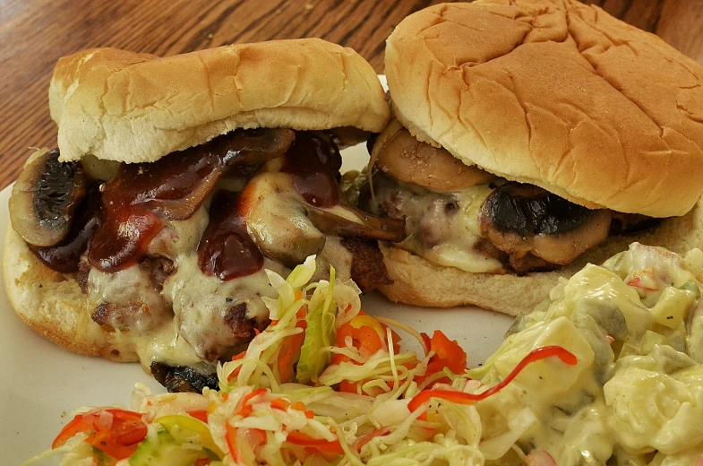 two hamburgers with toppings are sitting on a plate