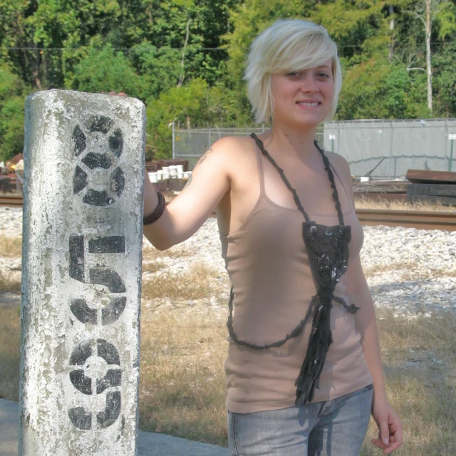 a woman poses next to a graffiti writing sign
