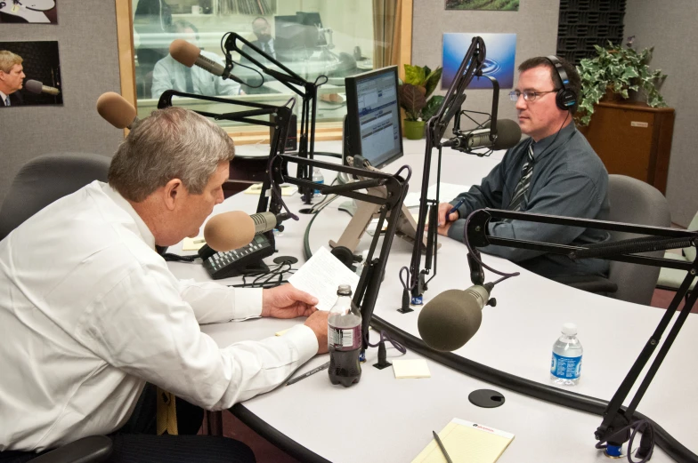 a man sitting at a table with microphones on it