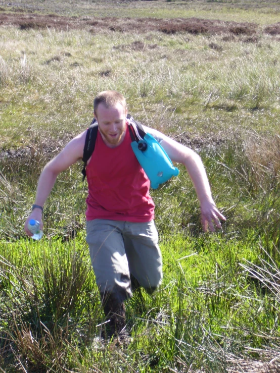 a young man in the middle of a field wearing green pants