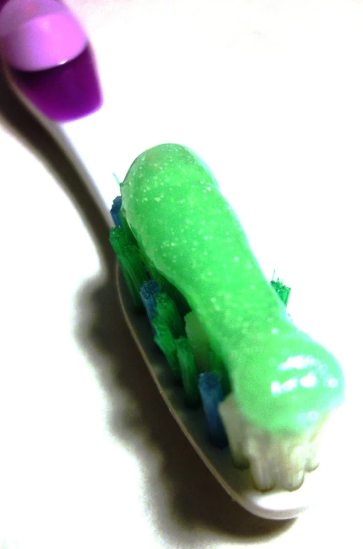 toothbrush with green and blue colored tooth paste on it