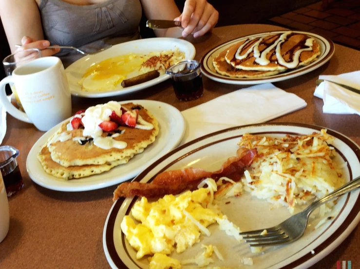 a breakfast plate with eggs and bacon, pancakes, coffee