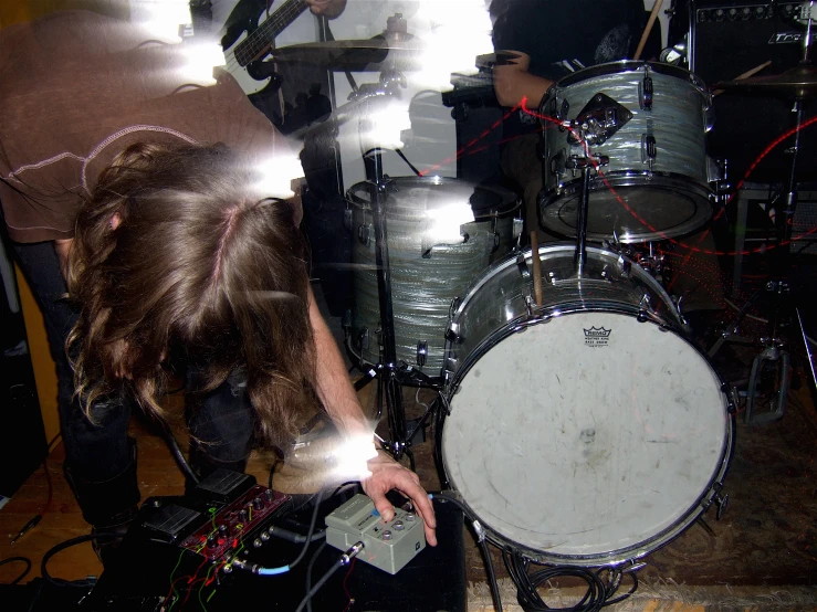 a man plays drums as others look on from behind