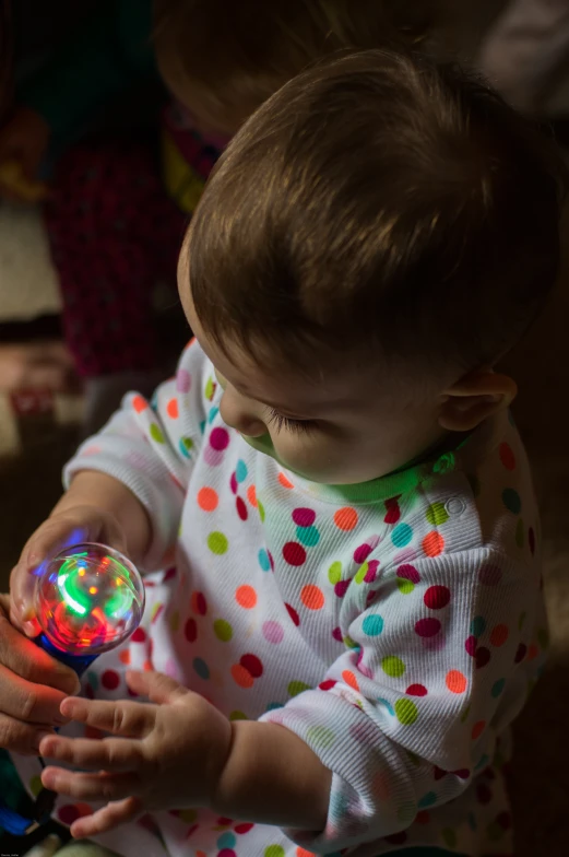 a baby playing with a colorful light ball