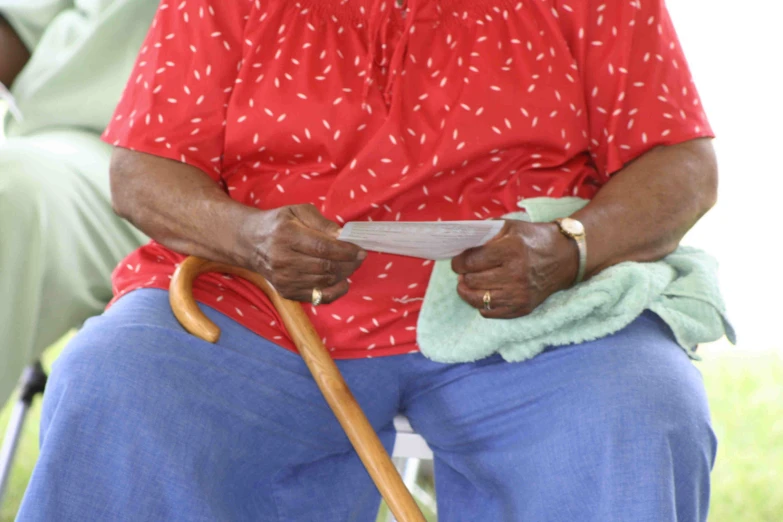 a woman with a cane holding a paper on a field