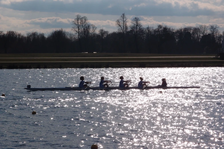 four people are rowing in a boat across the water