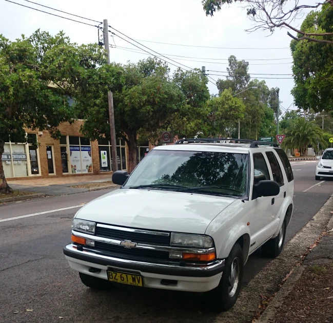 an suv parked in front of a street with many trees