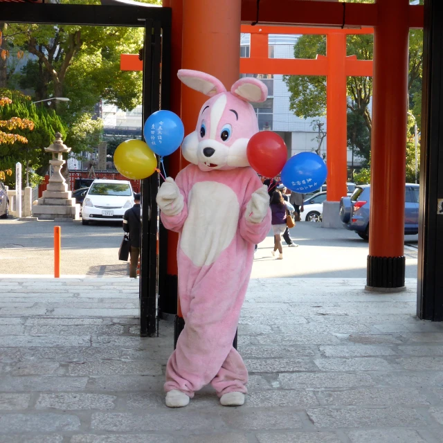 a bunny mascot stands next to an arch in a public area